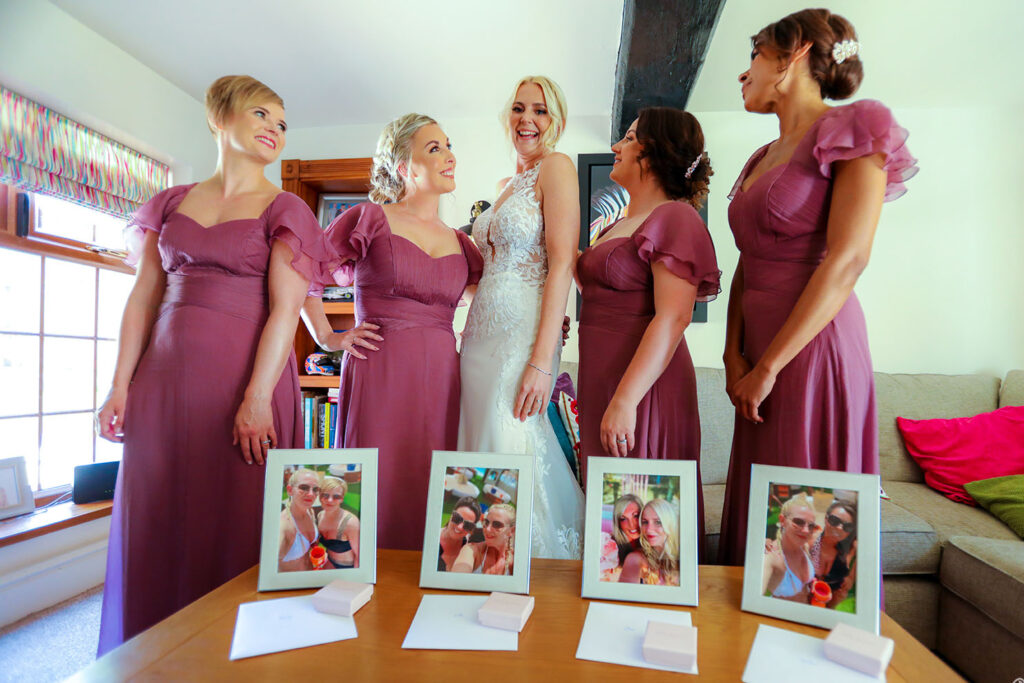 Bridal team in maroon attire indoors, portraits displayed on the table.